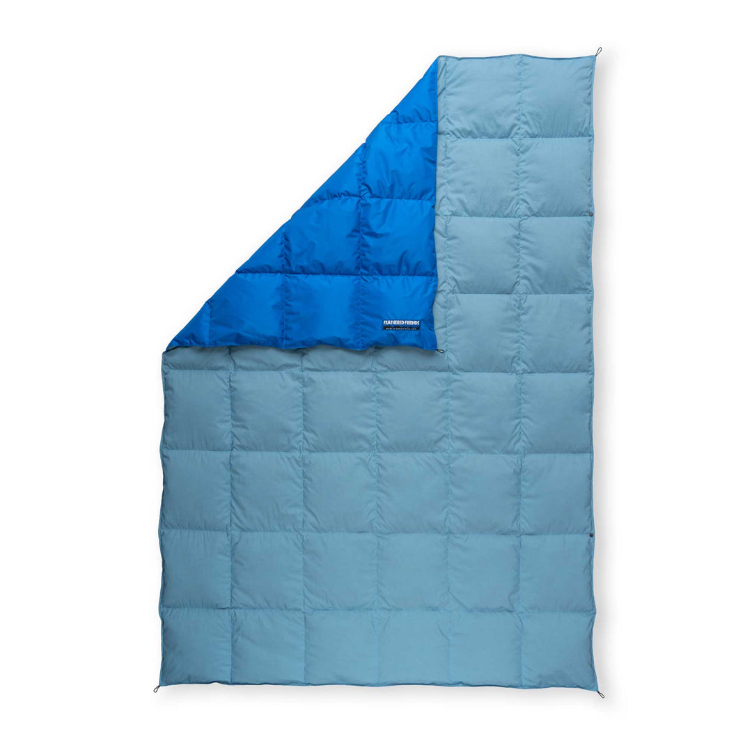 Light blue and dark blue Feathered Friends water-resistant down blanket on a white background