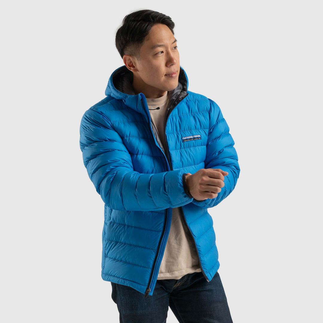 Front view studio photo of a man wearing blue sky color Feathered Friends Eos Jacket