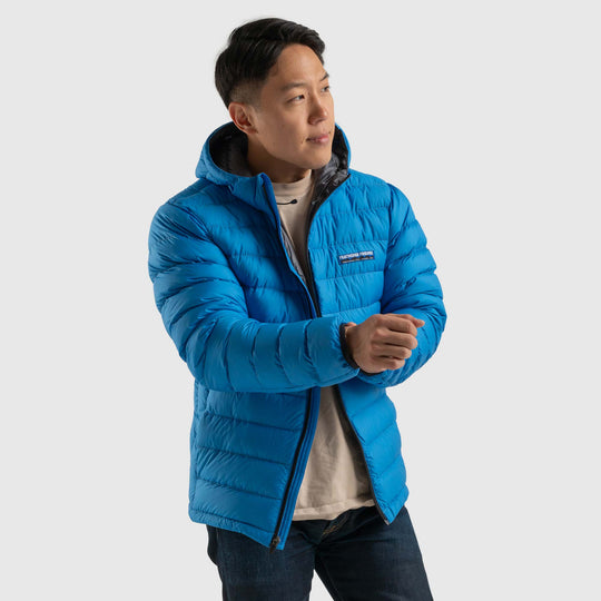 Front view studio photo of a man wearing blue sky color Feathered Friends Eos Jacket