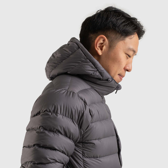 Side view studio photo of a man wearing Steel Gray color Feathered Friends Eos Jacket