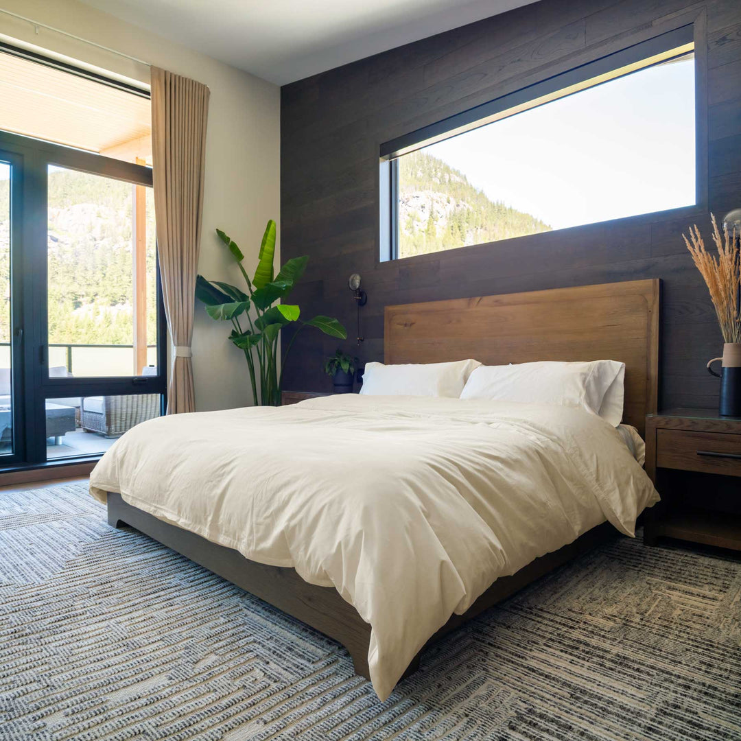 Ivory-color Feathered Friends Organic Cotton Duvet Cover set on a wood bed in a mountain lodge