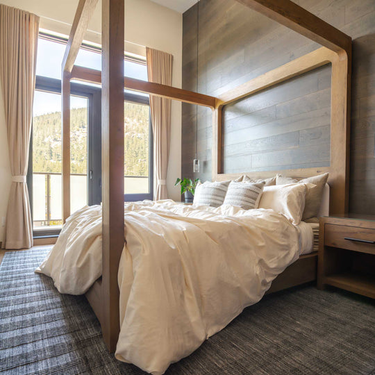 Natural Feathered Friends Organic Cotton Duvet Cover set flowing off a 4-post wood bed in a mountain lodge