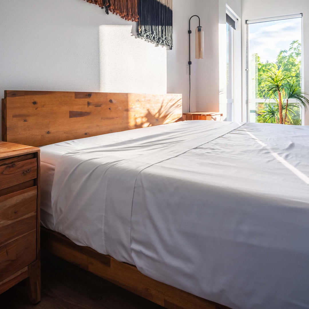 White Feathered Friends Organic Cotton Flat Sheet on a wood bed