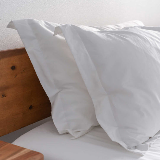 White Feathered Friends Organic Cotton pillow sham details on a wood bed