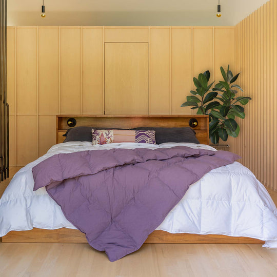Bedroom with wood panel walls with a bed and Dusky Purple down throw blanket