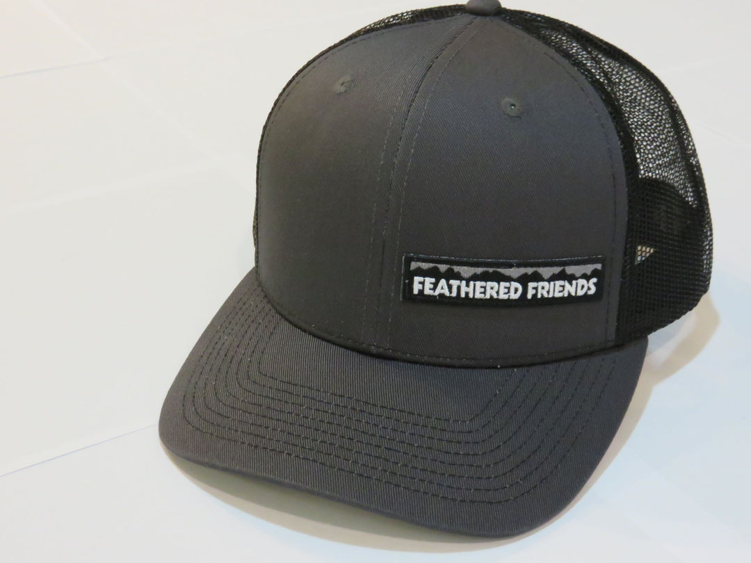 Studio image Feathered Friends Pro Style Offset Logo Trucker Hat dark grey and black colors