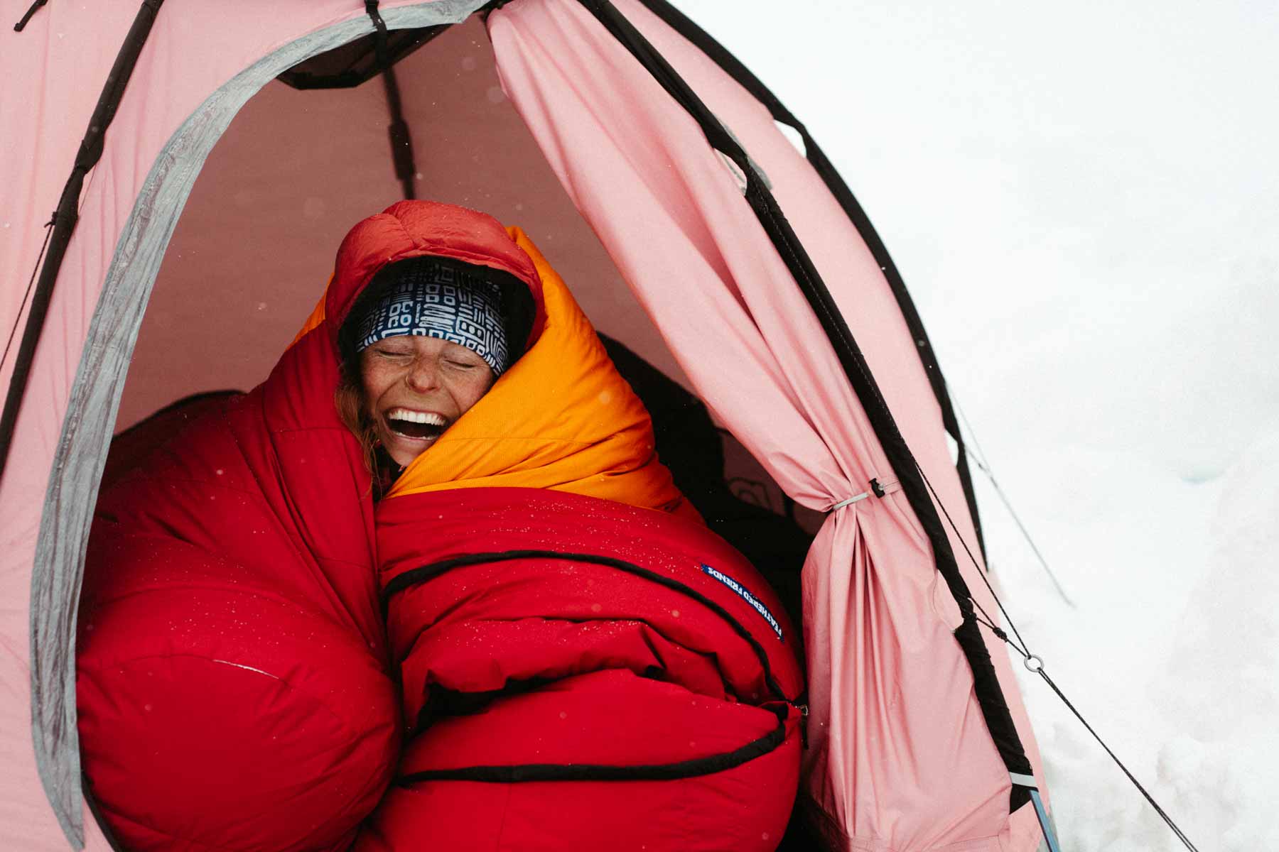 Woman in a tent wrapped in a Feathered Friends winter down sleeping bag