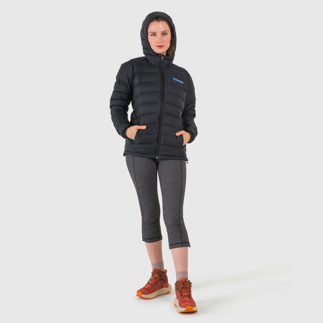Studio front view of woman wearing a black Women's Feathered Friends Eos Down Jacket with hood up