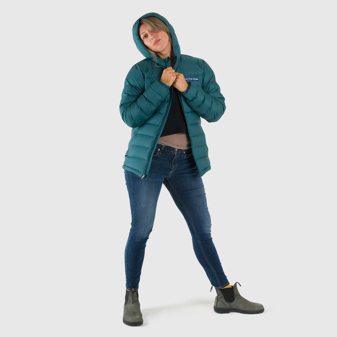 Studio front view of woman wearing an unzipped deep teal Women's Feathered Friends Eos Down Jacket