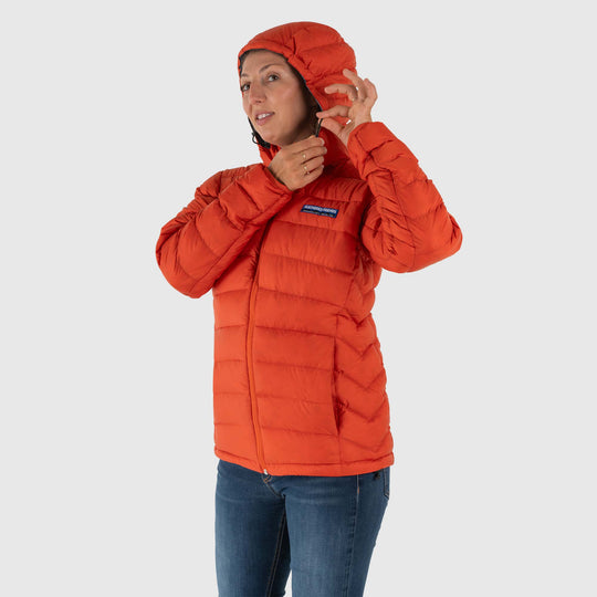 Studio front hood detail view of woman wearing a rorange Women's Feathered Friends Eos Down Jacket