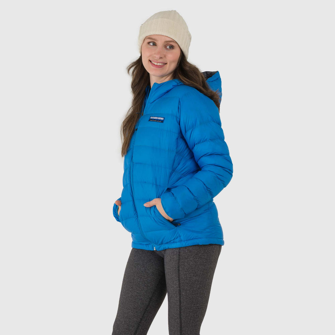 Studio front view of woman wearing a sky blue Women's Feathered Friends Eos Down Jacket
