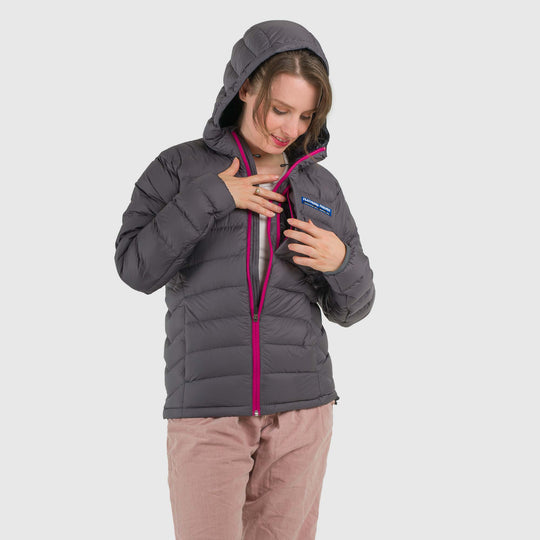 Studio front view of a woman wearing a steel gray Women's Feathered Friends Eos Down Jacket with front pocket detail