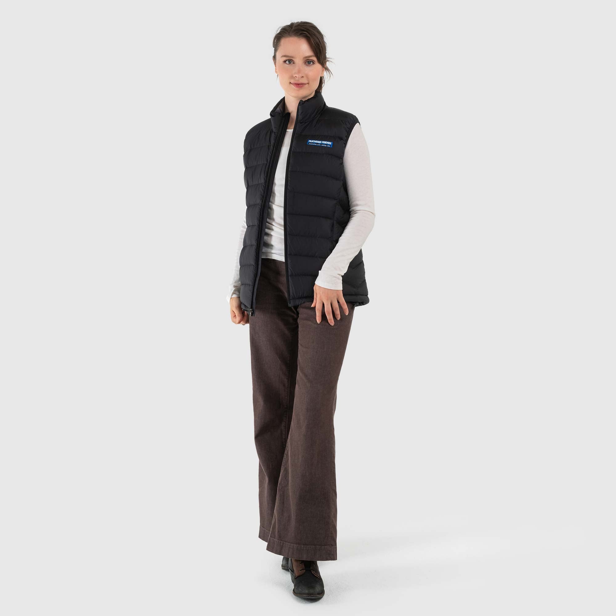Studio front view of a woman wearing a black Women's Feathered Friends Eos Down Vest