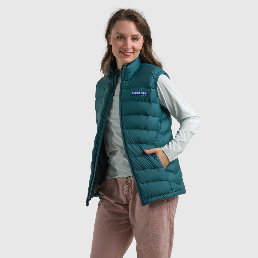 Studio front view of a woman wearing a deep teal Women's Feathered Friends Eos Down Vest