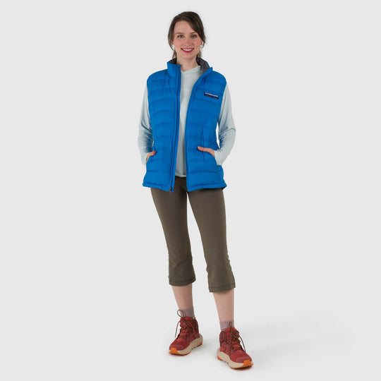 Studio front view of a woman wearing a sky blue Women's Feathered Friends Eos Down Vest