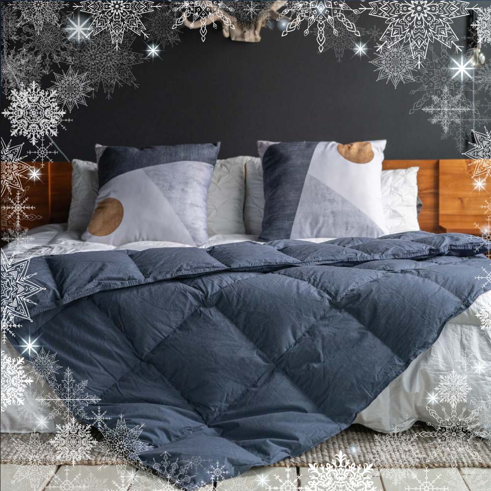 A navy-color Feathered Friends Organic Down Throw on a bed with a border of snowflakes