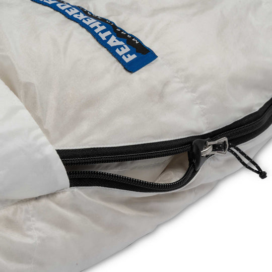 Close-up zipper detail on Feathered Friends Egret UL ultralight women's down sleeping bag in Undyed Pertex Quantum Pro on a white background
