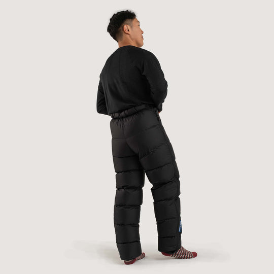 Studio back view of a man wearing a black Feathered Friends Helios down pants