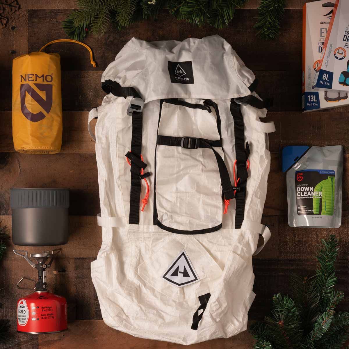 White Hyperlite backpack with black straps on a wooden surface with camping gear around it.