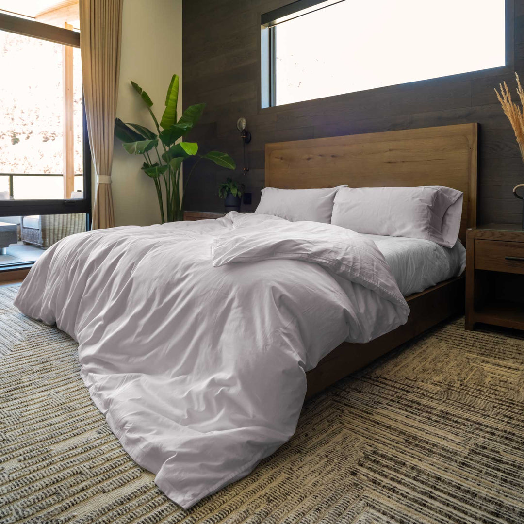 Thistle-color Feathered Friends Organic Cotton Duvet Cover and two Pillow Shams on a king-size bed in a mountain lodge