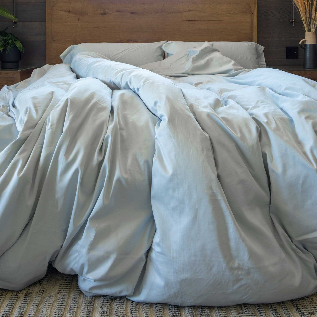 Horizon-blue color Feathered Friends Organic Cotton Duvet Cover set flowing off a wood bed in a mountain lodge