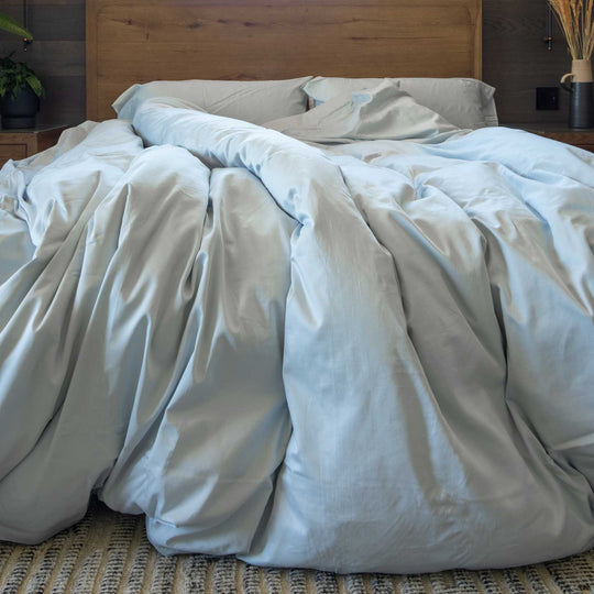 Horizon-blue color Feathered Friends Organic Cotton Duvet Cover set flowing off a wood bed in a mountain lodge