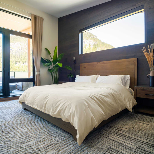 Ivory-color Feathered Friends Organic Cotton Duvet Cover set on a wood bed in a mountain lodge