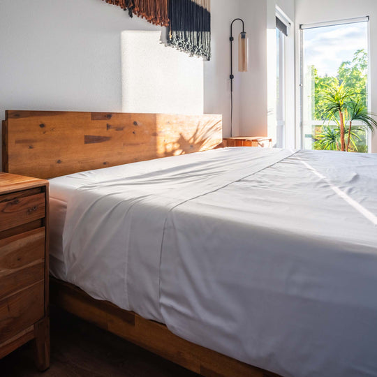 White Feathered Friends Organic Cotton Flat Sheet on a wood bed