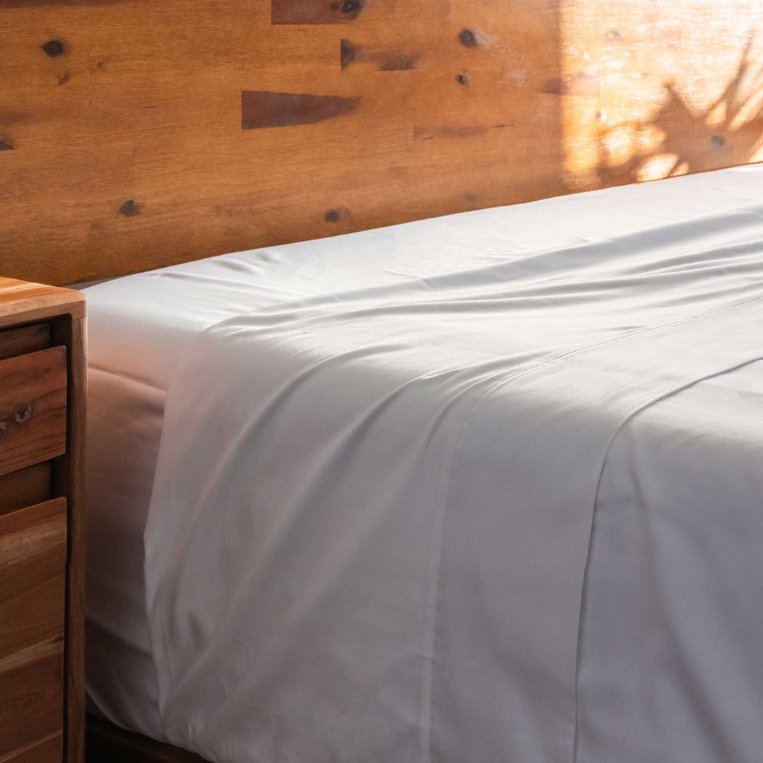 White Feathered Friends Organic Cotton Flat Sheet on a wood bed close up detail