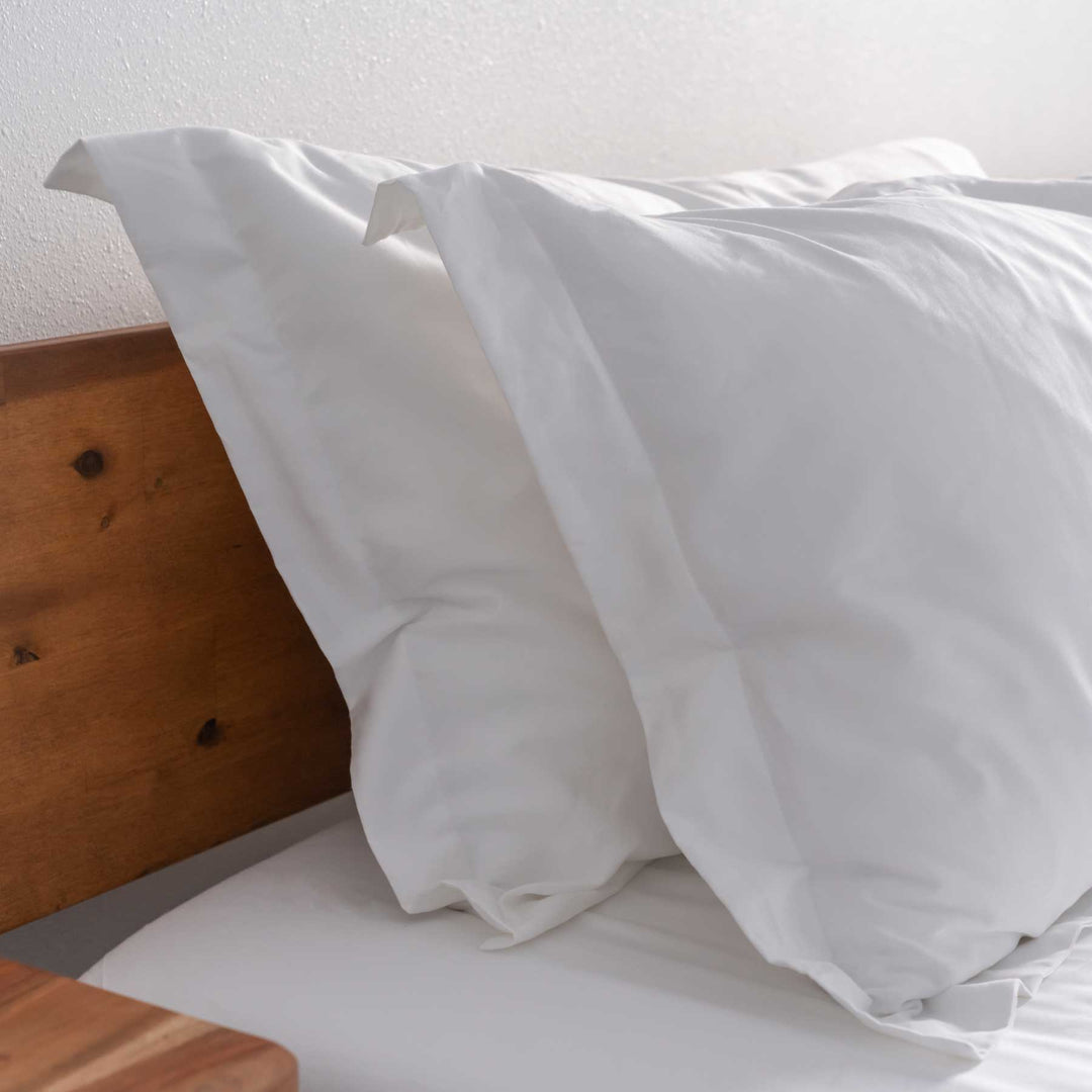 White Feathered Friends Organic Cotton pillow sham details on a wood bed