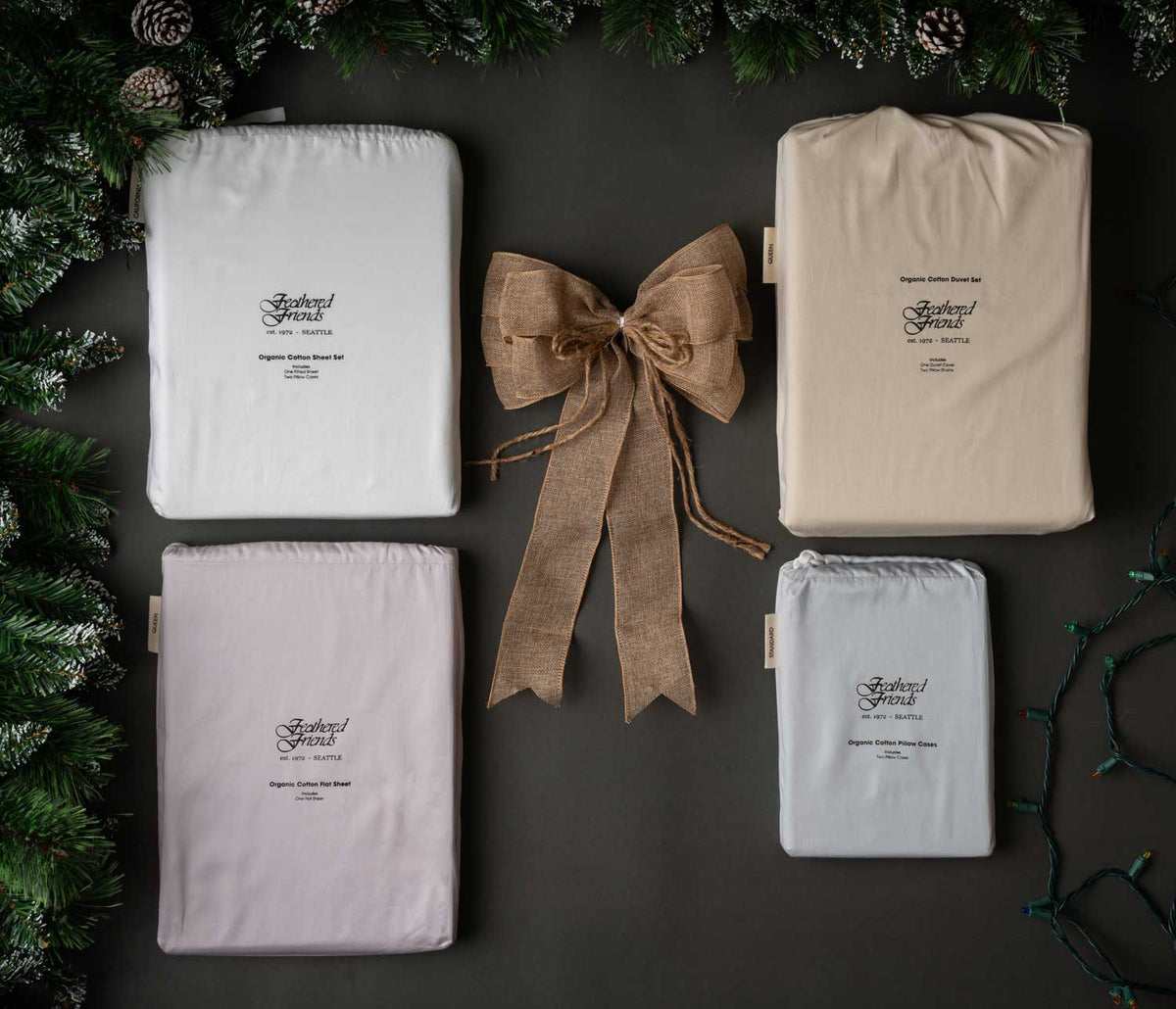 Feathered Friends Organic Cotton sheet products with a brown bow and pine boughs