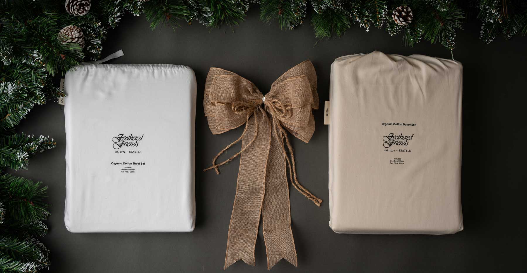 Natural Feathered Friends Duvet Cover Set and White Cotton Sheet Set on a gray background with brown bow and pine boughs
