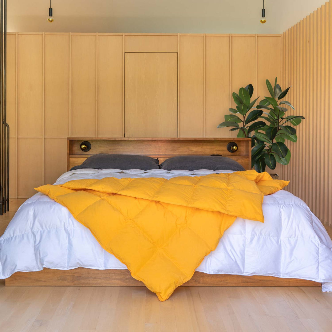 Bedroom with wood panel walls with a bed and Marigold yellow down throw blanket