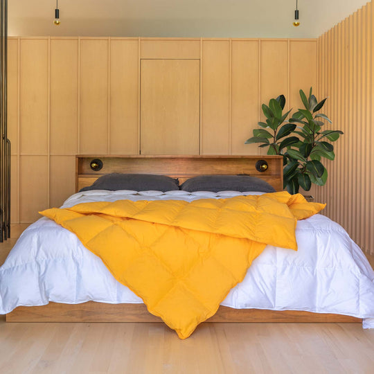Bedroom with wood panel walls with a bed and Marigold yellow down throw blanket