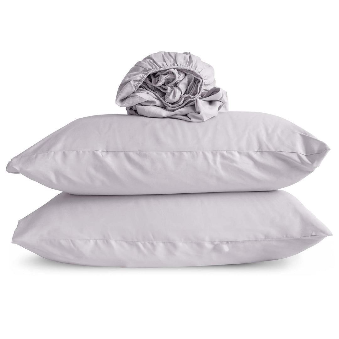 Studio photo of Thistle-color Feathered Friends Organic Cotton Fitted Sheet rolled up on two pillow cases
