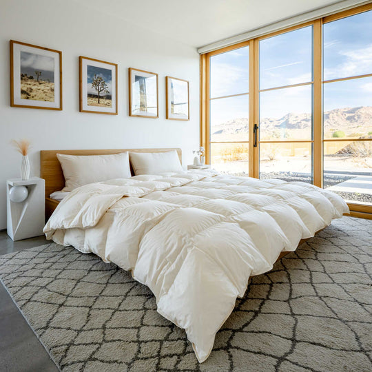 An organic cotton Feathered Friends Organic Bavarian down comforter on a bed in a bright bedroom in a desert setting