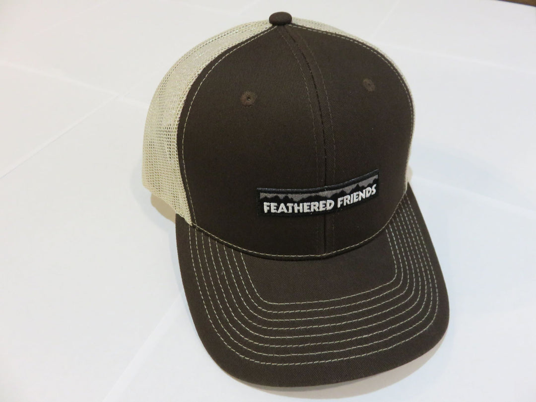 Studio image Feathered Friends Pro Style Mountain Logo Trucker Hat charcoal brown and tan colors