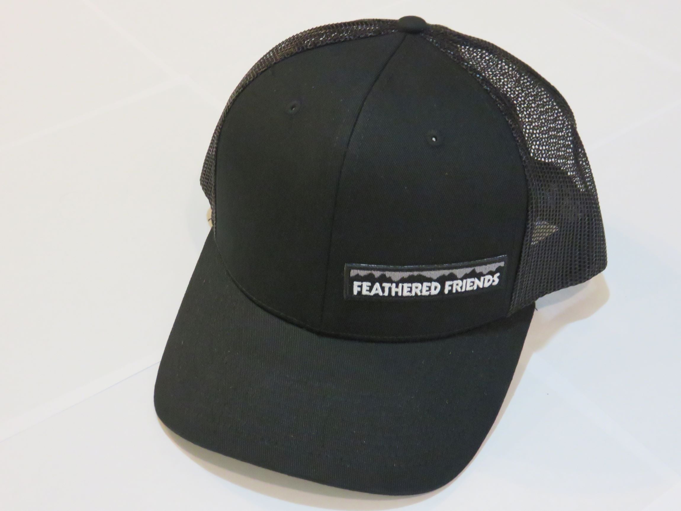 Studio image Feathered Friends Pro Style Offset Logo Trucker Hat black and black colors