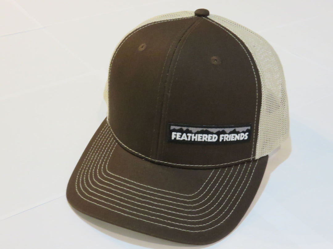 Studio image Feathered Friends Pro Style Offset Logo Trucker Hat charcoal brown and tan colors