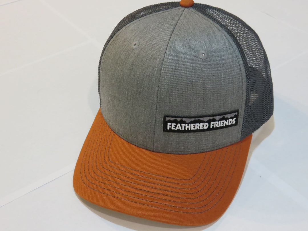 Studio image Feathered Friends Pro Style Offset Logo Trucker Hat heather gray and burnt orange with brown colors
