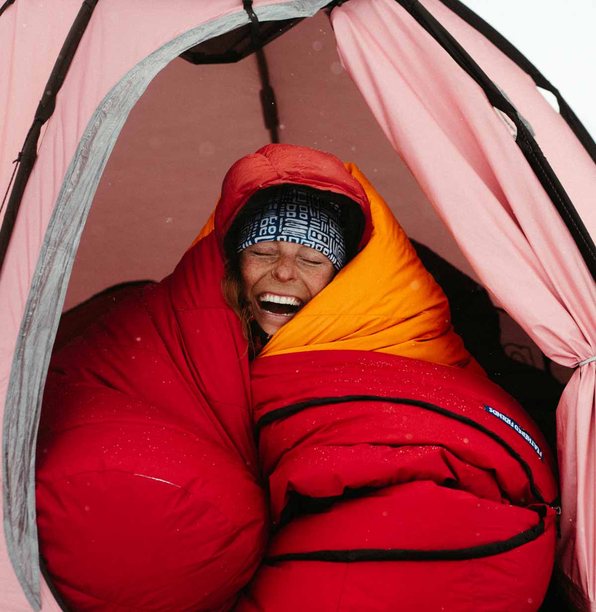 Woman in a tent wrapped in a Feathered Friends winter down sleeping bag