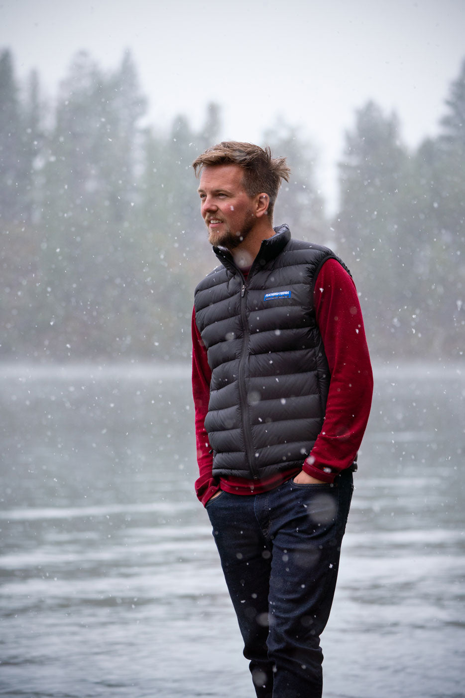 The Feathered Friends Men's Eos Down Vest, worn by a lake in the Rocky Mountains in autumn